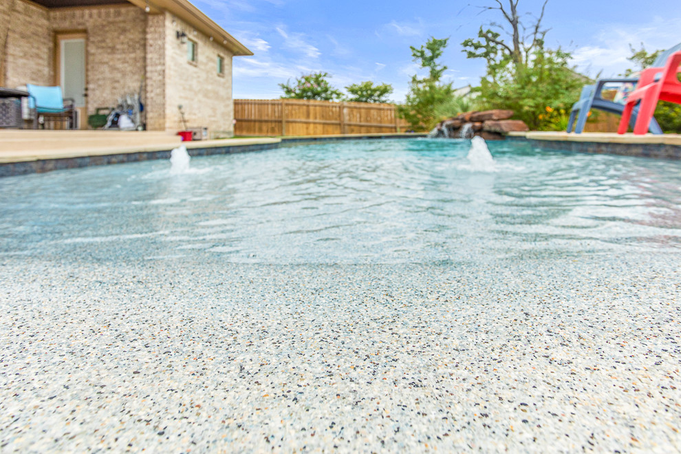 Imagen de piscina natural marinera de tamaño medio a medida en patio trasero con losas de hormigón