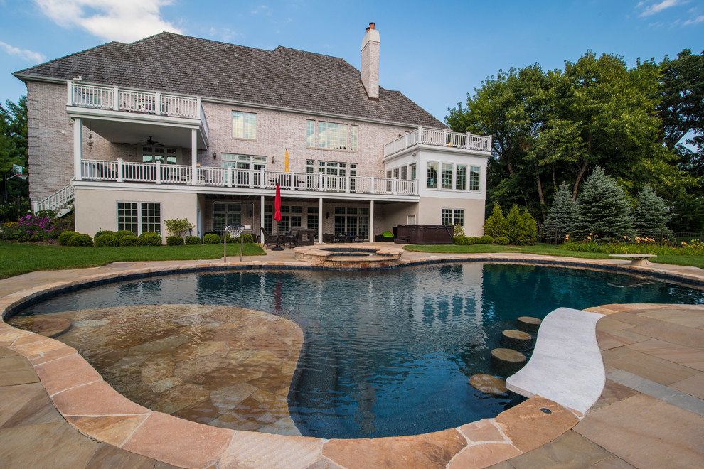 Immagine di una piscina naturale tradizionale personalizzata di medie dimensioni e dietro casa con una vasca idromassaggio e pavimentazioni in pietra naturale