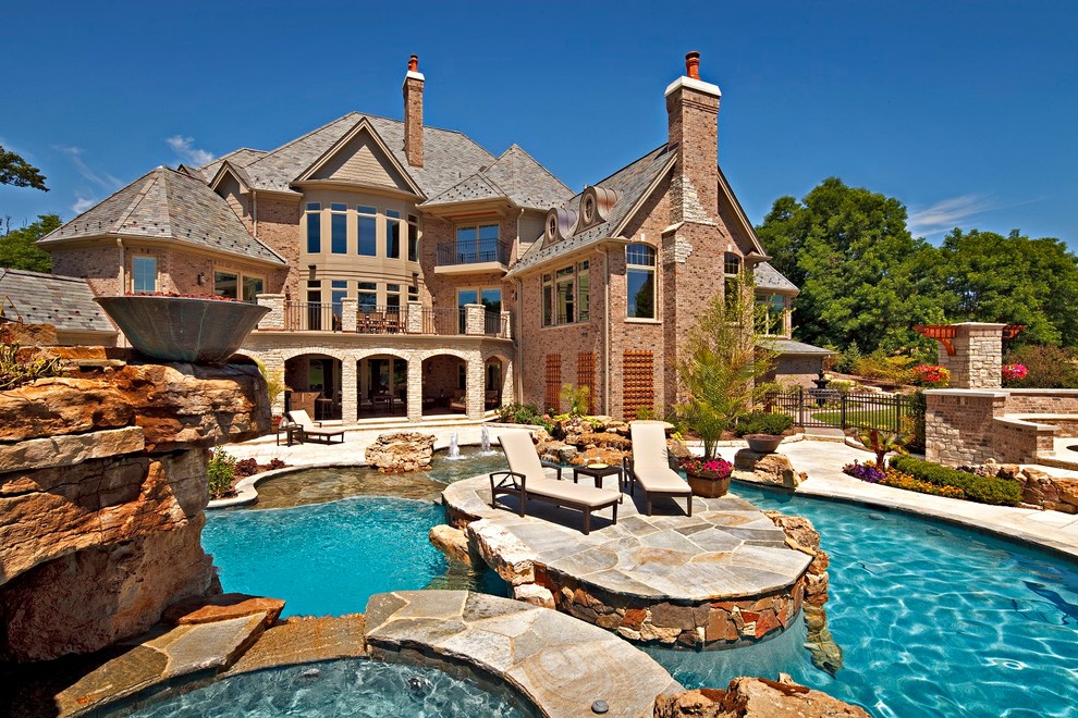 Esempio di una grande piscina naturale classica personalizzata dietro casa con pavimentazioni in pietra naturale e fontane