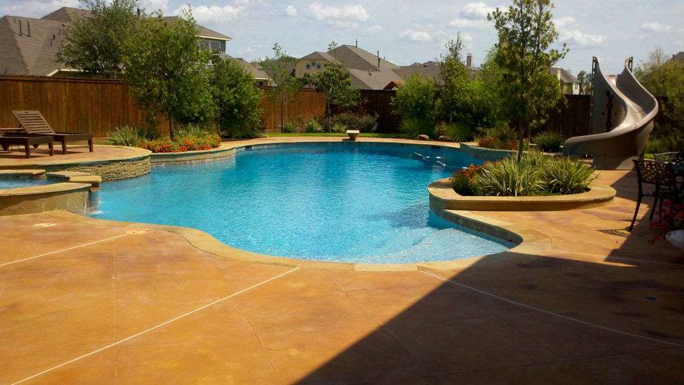 Immagine di un'ampia piscina naturale personalizzata dietro casa con lastre di cemento e una vasca idromassaggio