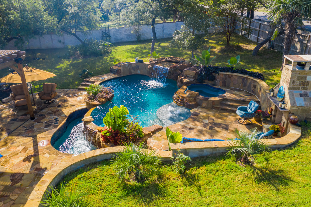 Modelo de piscina natural tropical grande a medida en patio trasero con entablado