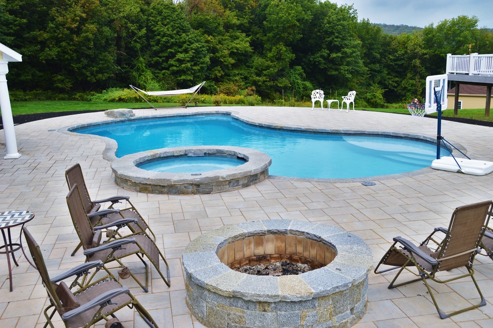 Стильный дизайн: естественный бассейн среднего размера, произвольной формы на заднем дворе в классическом стиле с джакузи и мощением тротуарной плиткой - последний тренд