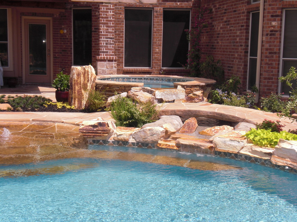 Ejemplo de piscinas y jacuzzis naturales clásicos de tamaño medio a medida en patio trasero con adoquines de piedra natural