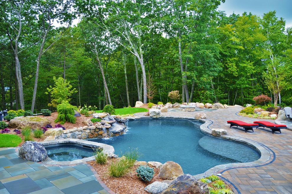 Foto di una grande piscina naturale tradizionale personalizzata dietro casa con una vasca idromassaggio e pavimentazioni in cemento