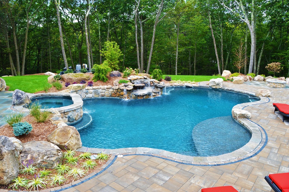 Photo of a large classic back custom shaped natural hot tub in Bridgeport with concrete paving.
