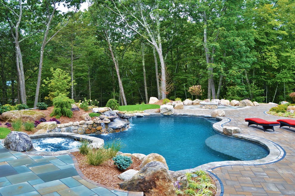 Ispirazione per una grande piscina naturale tradizionale personalizzata dietro casa con una vasca idromassaggio e pavimentazioni in cemento