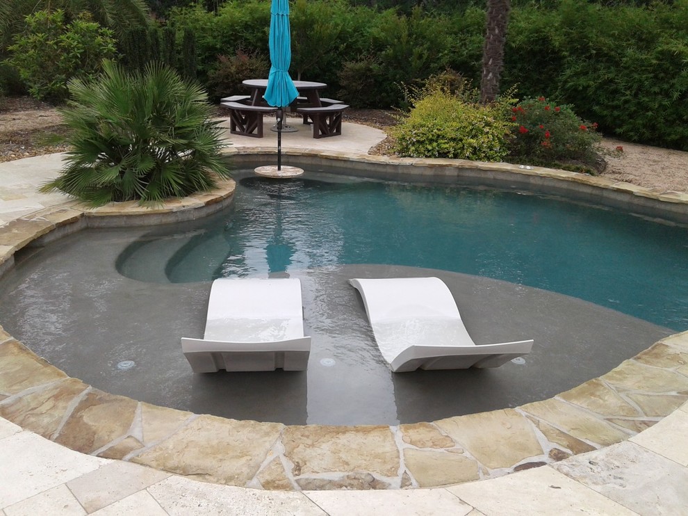 Freeform pool with tanning ledge, ledge loungers, rock waterfall