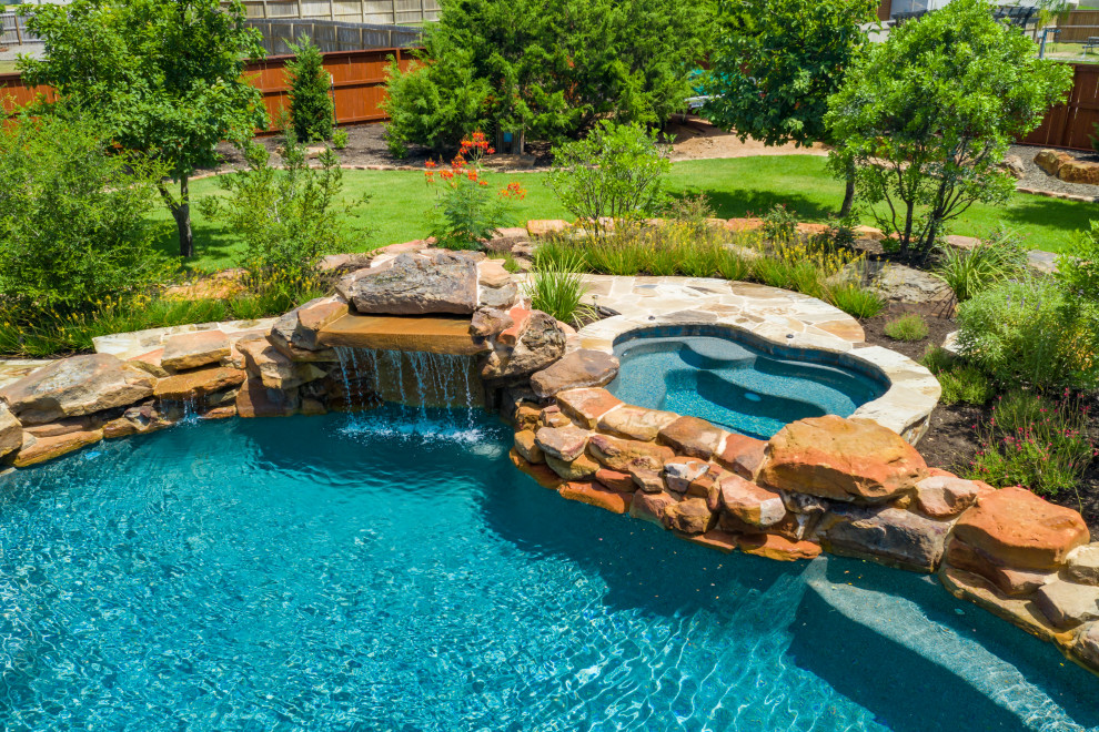 Cette photo montre une grande piscine naturelle et arrière chic sur mesure avec un bain bouillonnant et une terrasse en bois.