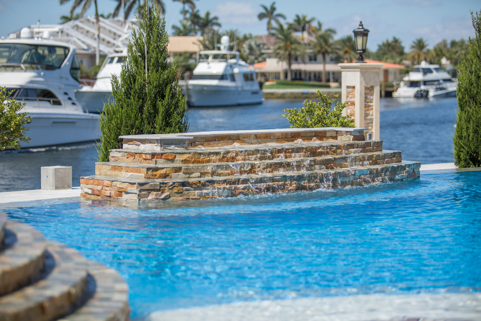 Ejemplo de piscina natural clásica extra grande a medida en patio trasero con adoquines de piedra natural