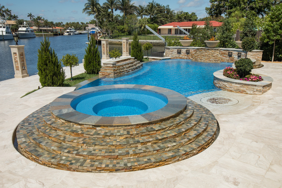 На фото: огромный естественный бассейн произвольной формы на заднем дворе в викторианском стиле с покрытием из каменной брусчатки