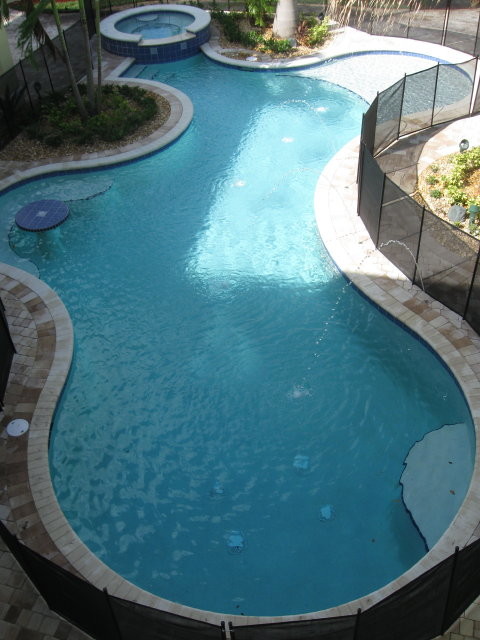 На фото: большой естественный бассейн произвольной формы на заднем дворе в морском стиле с мощением клинкерной брусчаткой