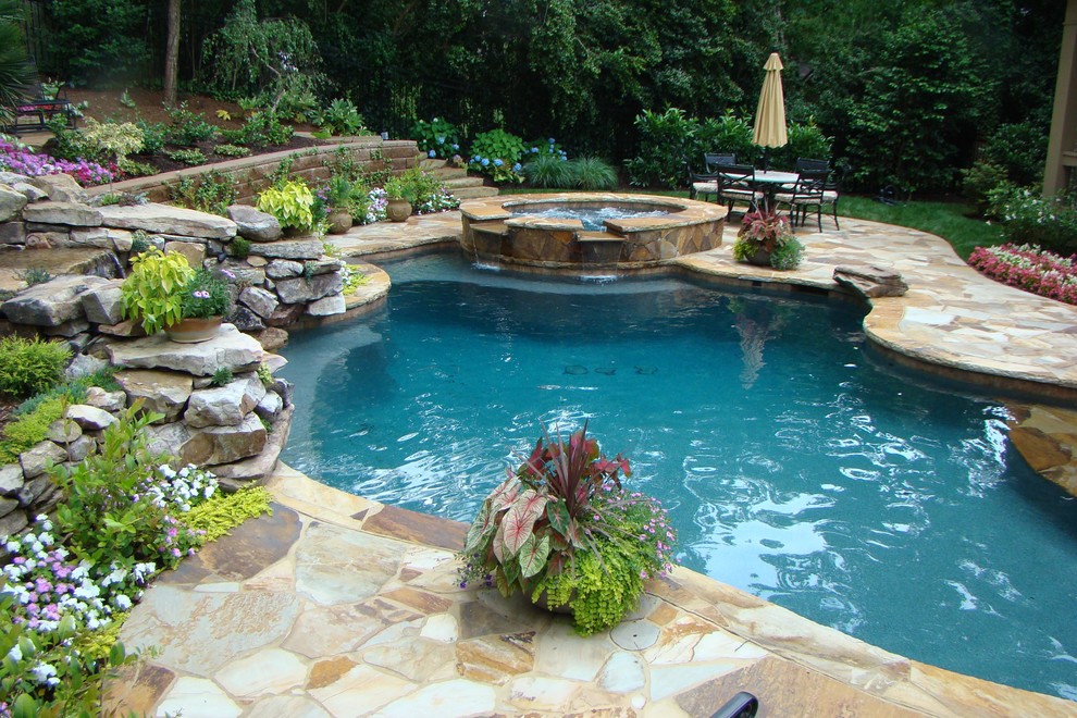 Exempel på en stor klassisk anpassad pool på baksidan av huset, med spabad och naturstensplattor