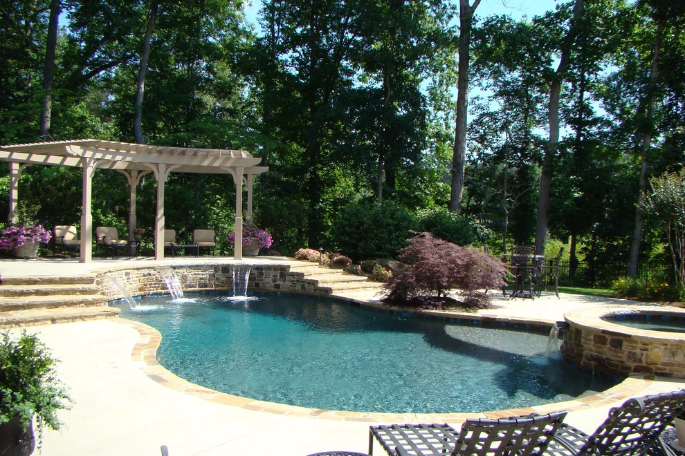 Klassisk inredning av en stor anpassad pool på baksidan av huset, med en fontän och naturstensplattor