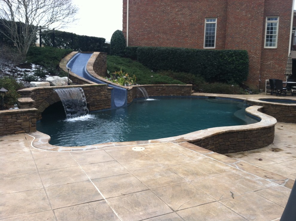 Esempio di una grande piscina tradizionale personalizzata dietro casa con fontane e pavimentazioni in pietra naturale