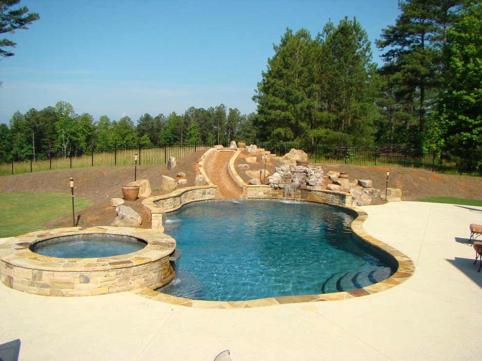 Inspiration för stora klassiska anpassad pooler på baksidan av huset, med vattenrutschkana och naturstensplattor