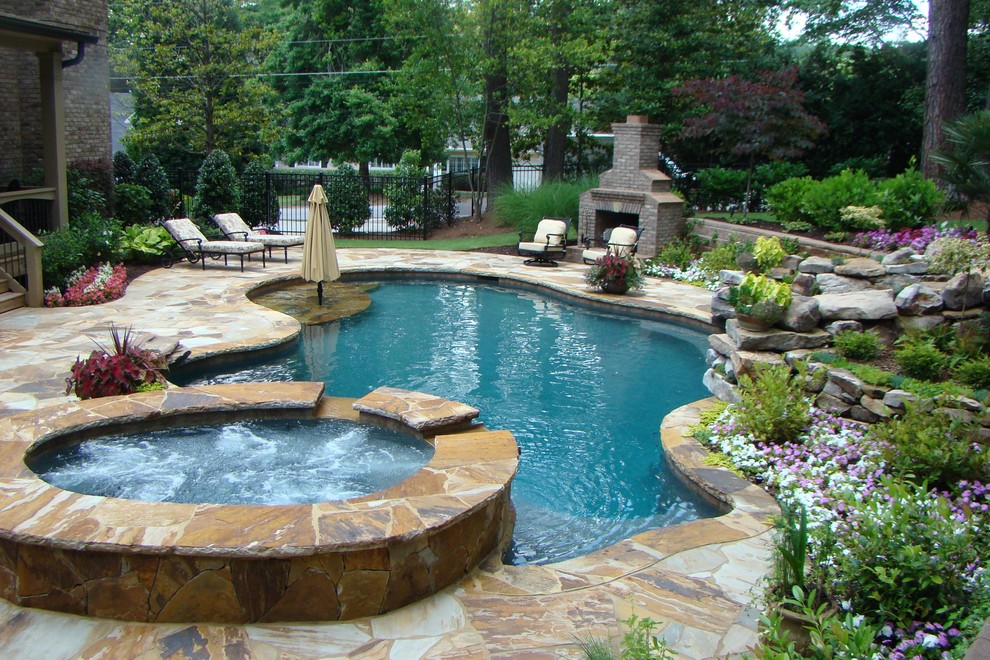 Imagen de piscinas y jacuzzis tradicionales de tamaño medio a medida en patio trasero con adoquines de piedra natural
