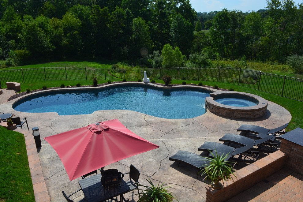 Foto di una grande piscina stile marinaro personalizzata dietro casa con una vasca idromassaggio e cemento stampato