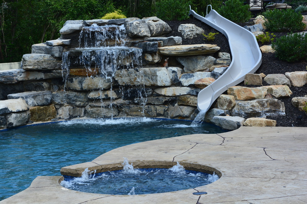 На фото: большой бассейн произвольной формы на заднем дворе в современном стиле с водной горкой и покрытием из декоративного бетона с
