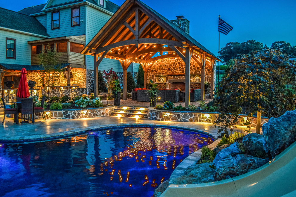 Imagen de piscina natural rústica grande a medida en patio trasero con paisajismo de piscina y adoquines de piedra natural