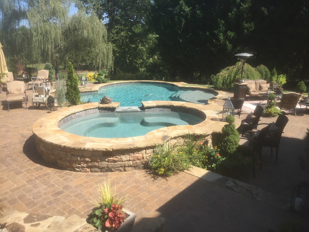 Ejemplo de piscina con fuente natural clásica grande a medida en patio trasero con adoquines de piedra natural