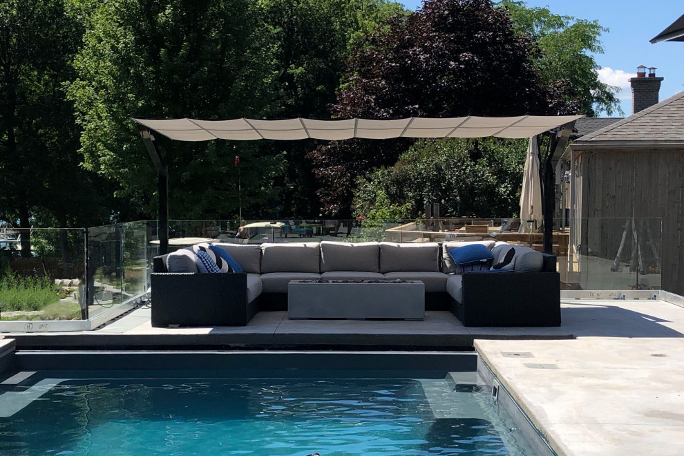 Modelo de piscina alargada minimalista grande rectangular en patio trasero con losas de hormigón