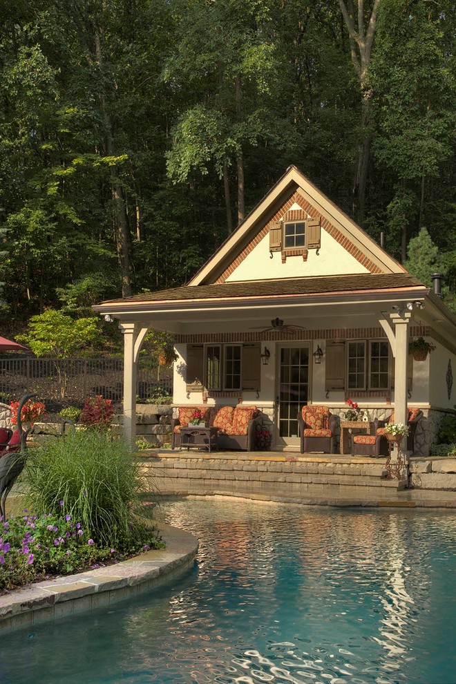 Ejemplo de casa de la piscina y piscina natural clásica de tamaño medio a medida en patio trasero con adoquines de piedra natural