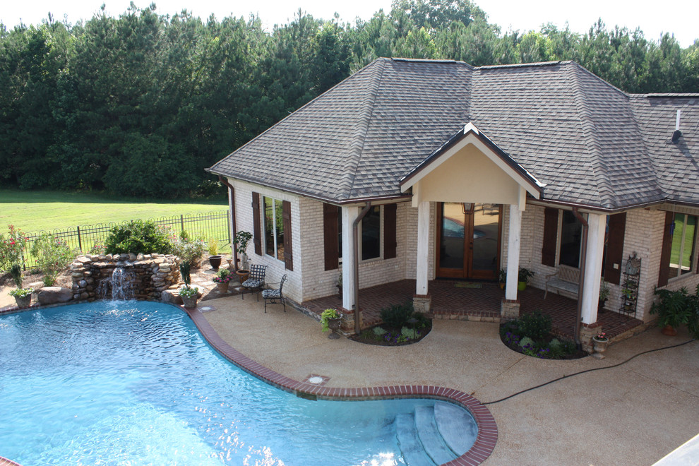 Foto di una grande piscina classica a "C" dietro casa con una dépendance a bordo piscina e pavimentazioni in pietra naturale