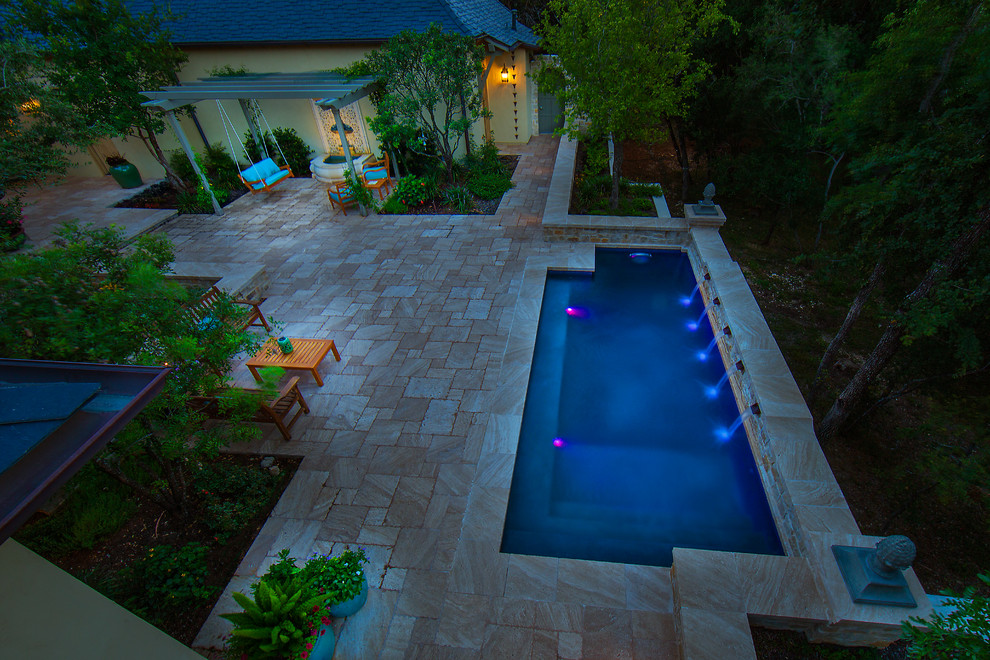 Imagen de piscina con fuente alargada tradicional de tamaño medio rectangular en patio trasero con adoquines de piedra natural