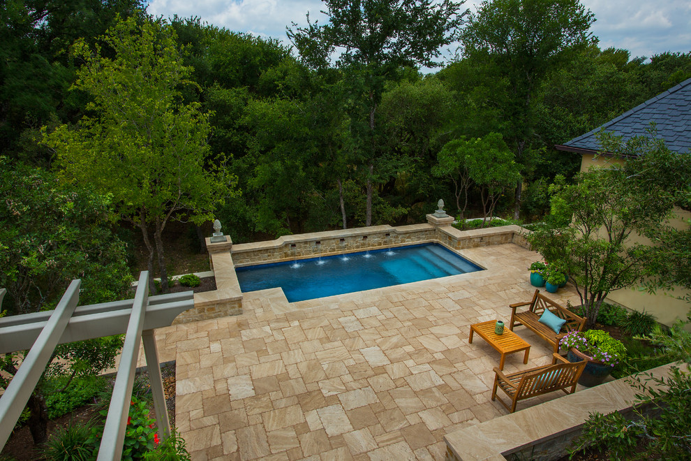 Ejemplo de piscina con fuente alargada clásica de tamaño medio rectangular en patio trasero con adoquines de piedra natural