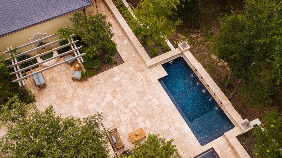 Diseño de piscina con fuente alargada clásica de tamaño medio rectangular en patio trasero con adoquines de piedra natural