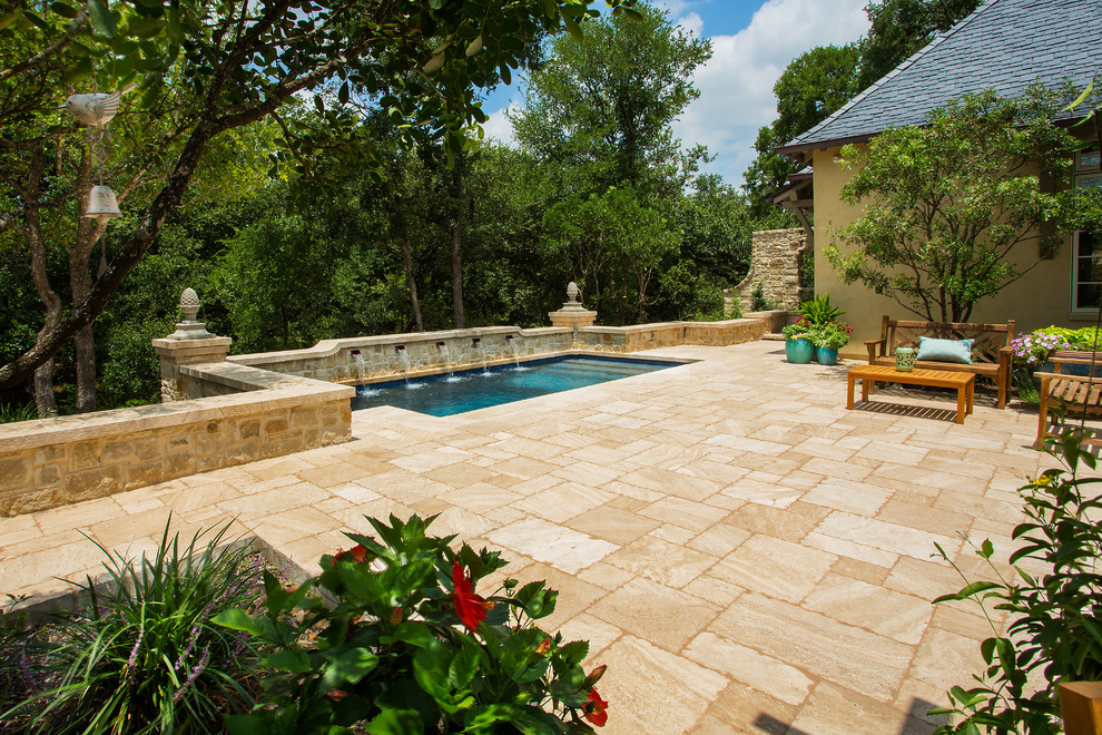 Ejemplo de piscina con fuente alargada tradicional de tamaño medio rectangular en patio trasero con adoquines de piedra natural
