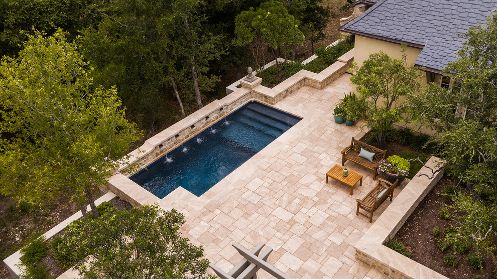 Modelo de piscina con fuente alargada clásica de tamaño medio rectangular en patio trasero con adoquines de piedra natural