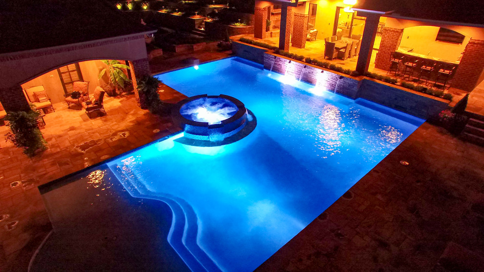 Diseño de piscina con fuente alargada clásica de tamaño medio en forma de L en patio trasero con adoquines de piedra natural