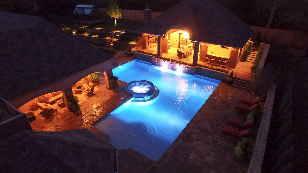 Modelo de casa de la piscina y piscina alargada tradicional de tamaño medio en forma de L en patio trasero con adoquines de piedra natural