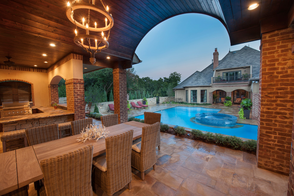 This is an example of a large modern back l-shaped lengths swimming pool in Oklahoma City with a pool house and natural stone paving.