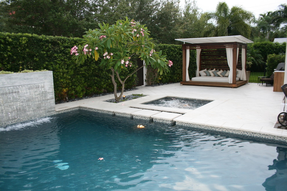 Esempio di una grande piscina a sfioro infinito chic rettangolare dietro casa con pedane e fontane