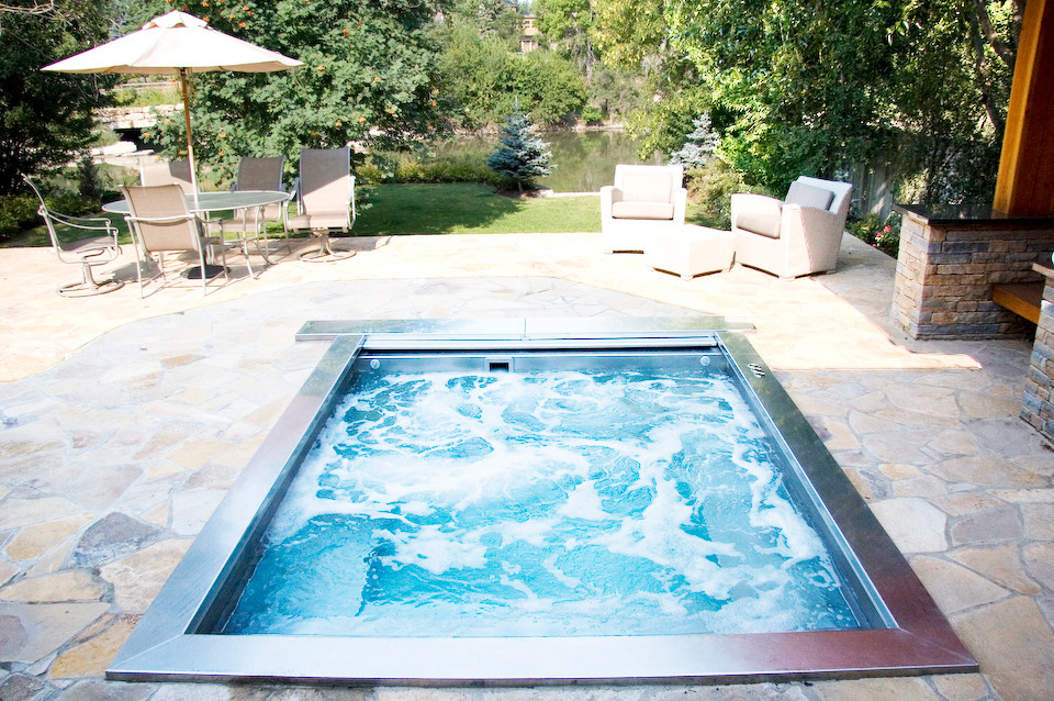 Cette image montre une piscine arrière urbaine avec un bain bouillonnant et des pavés en pierre naturelle.