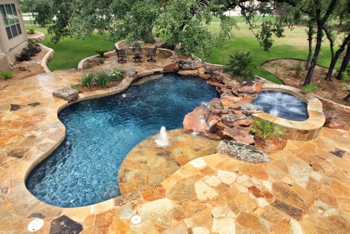 Пример оригинального дизайна: естественный бассейн среднего размера, произвольной формы на заднем дворе в стиле рустика с фонтаном и покрытием из каменной брусчатки