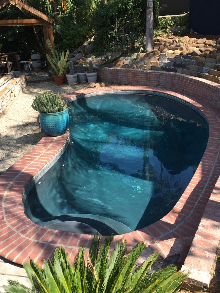 Diseño de piscina clásica de tamaño medio tipo riñón en patio lateral con gravilla