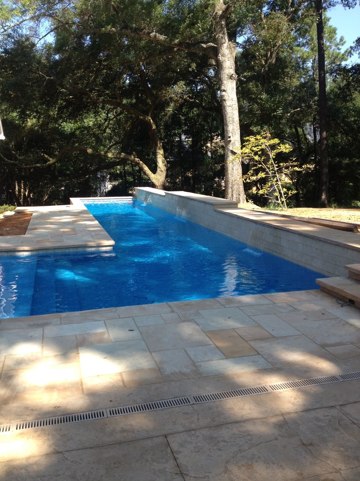 Esempio di una grande piscina monocorsia chic a "L" dietro casa con fontane e pavimentazioni in pietra naturale
