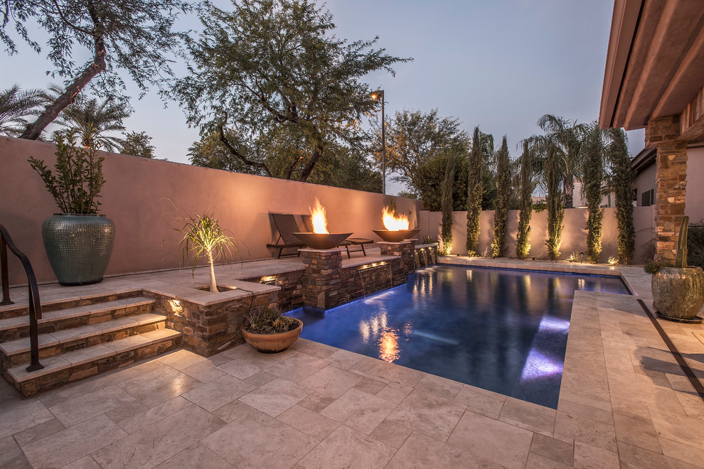 Modelo de piscina con fuente natural clásica renovada de tamaño medio en forma de L en patio trasero con adoquines de piedra natural