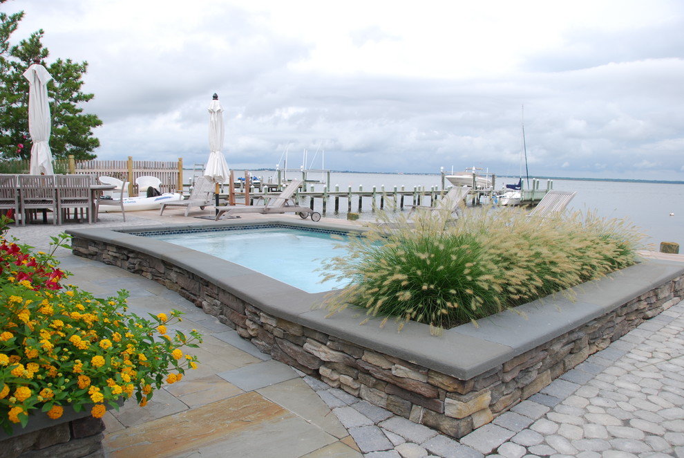Exemple d'une piscine arrière bord de mer rectangle avec des pavés en pierre naturelle.