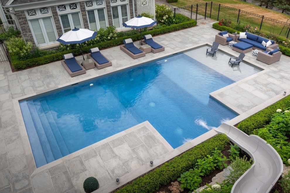 Imagen de piscina con tobogán contemporánea grande rectangular en patio lateral con adoquines de piedra natural