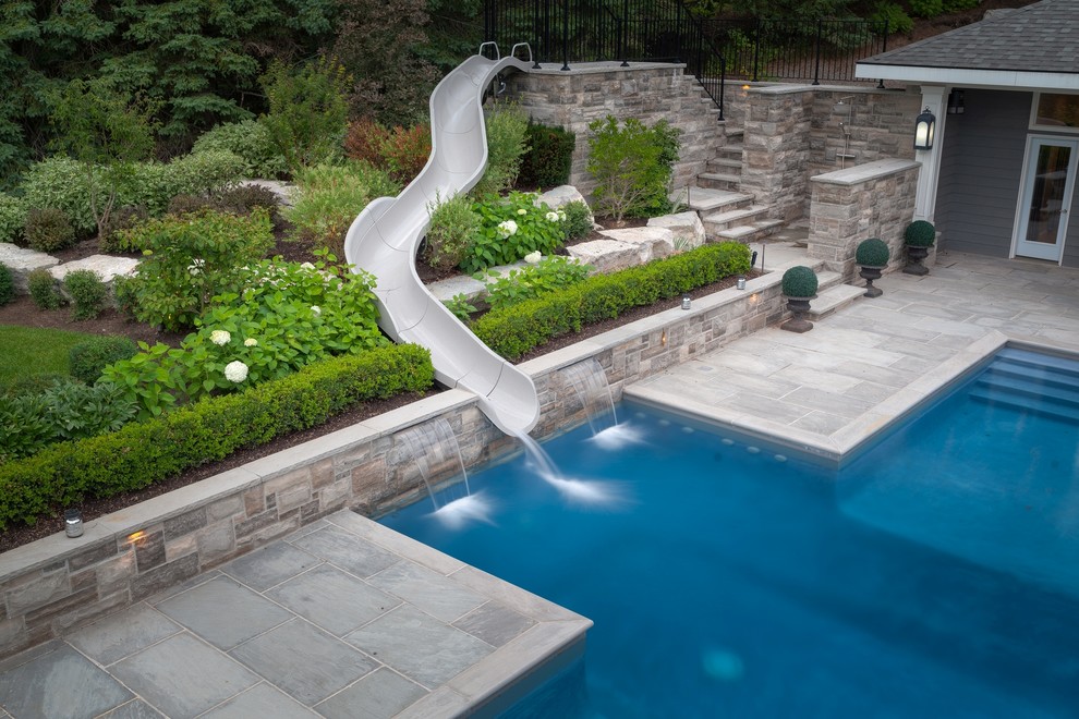 На фото: большой прямоугольный бассейн на боковом дворе в современном стиле с водной горкой и покрытием из каменной брусчатки с