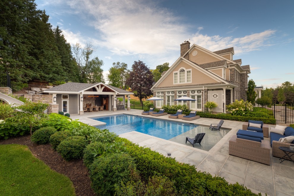 Ejemplo de casa de la piscina y piscina clásica grande rectangular en patio lateral con adoquines de piedra natural
