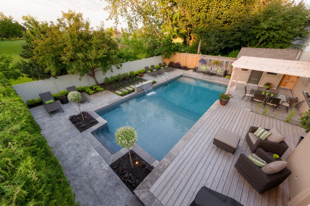 Diseño de piscina con fuente contemporánea de tamaño medio rectangular en patio trasero con suelo de hormigón estampado