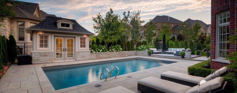Imagen de casa de la piscina y piscina contemporánea de tamaño medio rectangular en patio trasero con adoquines de piedra natural