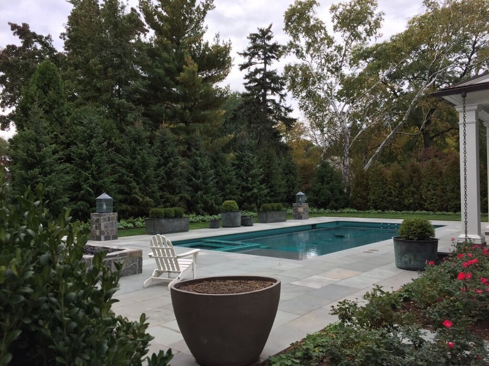 Ispirazione per una piscina monocorsia chic rettangolare di medie dimensioni e dietro casa con una vasca idromassaggio e pavimentazioni in pietra naturale