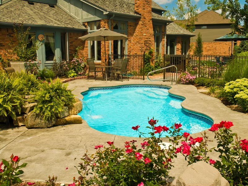 Imagen de piscina con fuente clásica de tamaño medio a medida en patio trasero con losas de hormigón