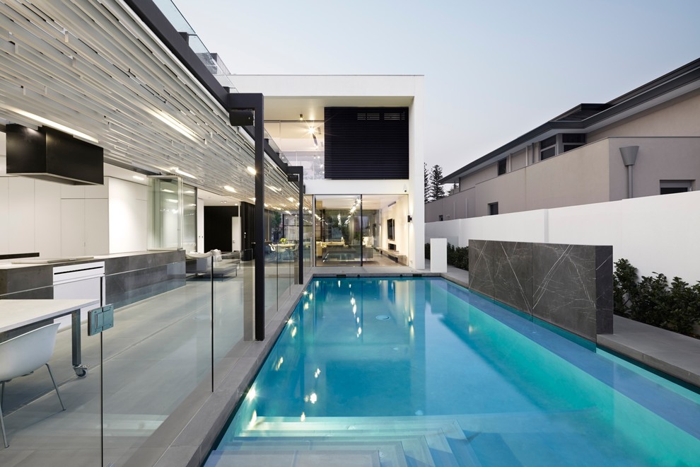 Foto de piscina con fuente alargada moderna grande en forma de L en patio con adoquines de piedra natural